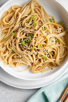 a white bowl filled with noodles and topped with sesame seeds