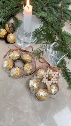 some chocolates are sitting next to a candle on the ground with christmas decorations around them