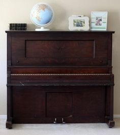 an old piano sitting on top of a white floor next to a globe and other items