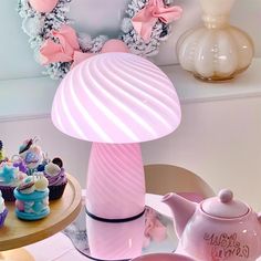 a pink lamp sitting on top of a table next to cupcakes and cakes