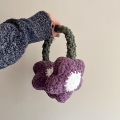 a hand holding a crocheted purse with a flower on the front and side