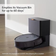 a robot vacuum is sitting on the floor in front of a wall with an ad that reads, empties its vacuum bin for up to 60 days