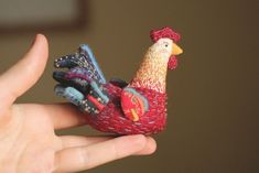 a hand holding a small toy chicken in it's palm