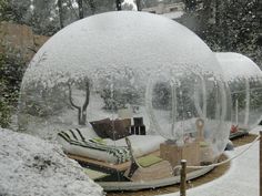 a large snow globe sitting in the middle of a yard filled with furniture and covered in snow