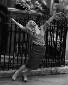 a woman leaning on a fence with her arms outstretched