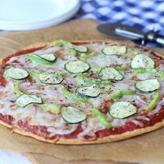 a pizza sitting on top of a wooden table covered in cheese and veggies