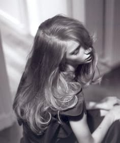 black and white photograph of a woman sitting on the floor with her hair blowing in the wind