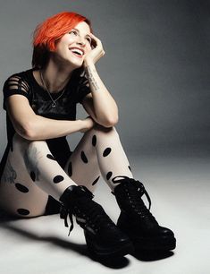 a woman with red hair sitting on the ground wearing black and white polka dot tights