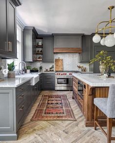 a kitchen with gray cabinets and white counter tops, an area rug on the floor