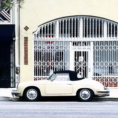 an old white car parked in front of a building