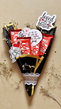 a bouquet of valentine's day chocolates in a black paper cone with gold accents