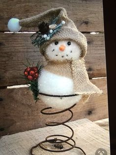 a snowman with a hat and scarf on it's head is sitting on top of a wire