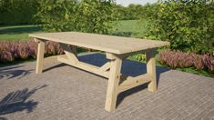 a wooden table sitting on top of a brick patio next to flowers and trees in the background