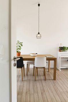 an open door leading to a dining room with wooden floors and white walls, along with two chairs