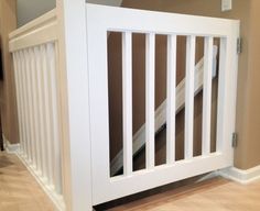 a white baby gate in the corner of a room with hardwood flooring and beige walls