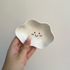 a hand holding a white bowl with a smiley face on it