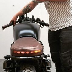 a man standing next to a motorcycle with its lights on and the back seat up