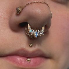 a close up of a person's nose with piercings on it and gold chains