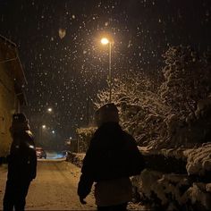 two people walking down a snowy street at night