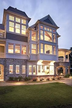 a large white house with lots of windows and lights on it's front porch