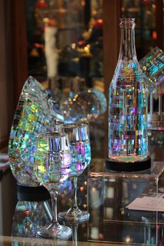 two wine glasses sitting on top of a glass table next to a bottle filled with liquid