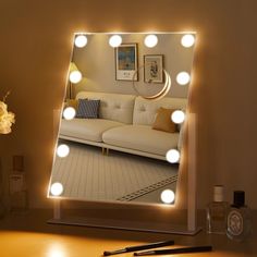 a mirror that has some lights on it in front of a table with a pen and flowers