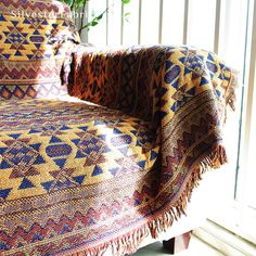 a couch covered in a colorful blanket next to a potted plant on a window sill