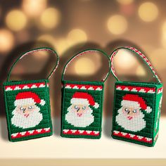 three small christmas bags with santa claus on them, one is green and the other is red