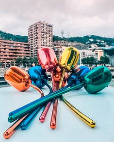 colorful metal spoons sitting on top of a white surface in front of tall buildings