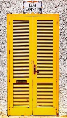 two yellow doors on the side of a building with a sign that says casa carpe - diem