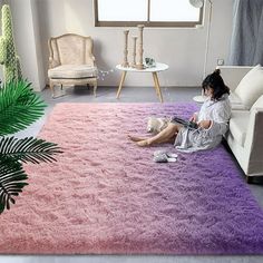 a woman sitting on a purple rug in a living room next to a white couch