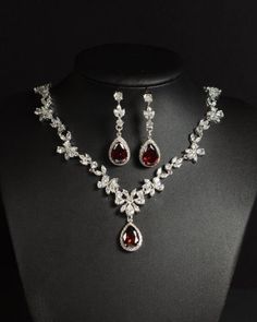 a necklace and earring set with red stones on a mannequin neckline