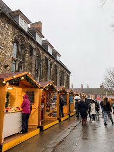 people are walking down the street in front of stalls with christmas decorations on them and lights strung up