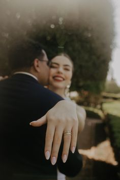 a man and woman standing next to each other with their hands on the back of them