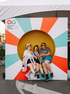 three people sitting on top of a large colorful object in the middle of a street