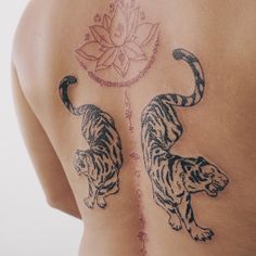 the back of a woman's body with tiger tattoos on her upper and lower half