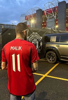 a man in a red shirt standing next to a truck