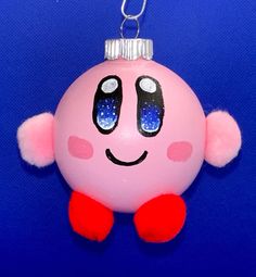 a pink ornament with blue and white dots on it's face is hanging from a chain