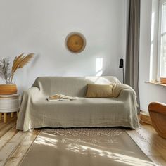 a living room with white walls and wood flooring on the wooden floors is furnished with an overstuffed sofa