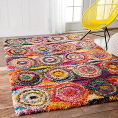 a multicolored area rug on the floor with a yellow chair in the background