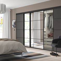 a bedroom with a bed, chair and mirrored closet doors