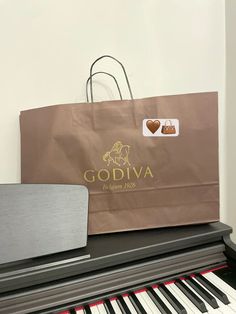 a brown paper bag sitting on top of a piano with the words godiva written on it