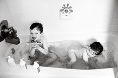 two children are in the bathtub with soap and toothbrushes