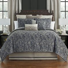 a blue and white comforter set with two lamps on either side of the bed