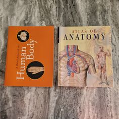 two books sitting on top of a marble floor next to each other, one with an atlas of anatomy