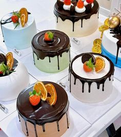 many different types of cakes on display for sale in a store or showroom, including one with strawberries and oranges