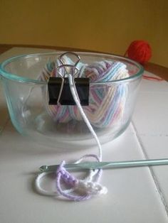 a glass bowl with yarn in it and a crochet hook on the side