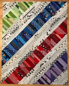 a close up of a quilt on a wooden floor with many different colors and patterns