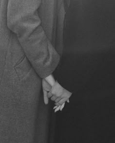 two people are holding hands in black and white photo, one is wearing a suit