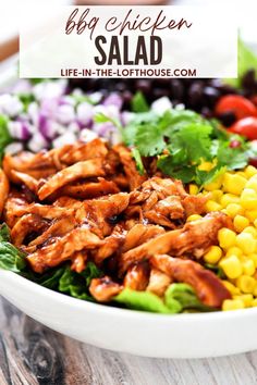 chicken salad with lettuce, corn and tomatoes in a white bowl on a wooden table